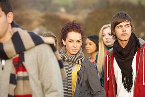Teenage Girl Surrounded By Friends In Outdoor Autumn Landscape