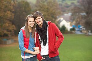 Romantic Teenage Couple Walking Through Autumn Landscape