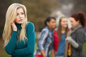 Upset Teenage Girl With Friends Gossiping In Background