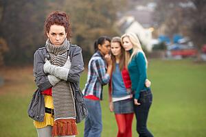 Upset Teenage Girl With Friends Gossiping In Background