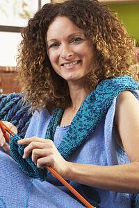 Close Up Of Woman Sitting In Chair Knitting