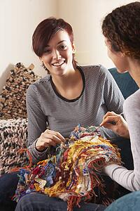 Two Women Knitting Together At Home