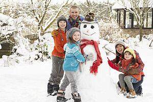 Family Building Snowman In Garden
