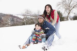 Family In Snow Riding On Sledge