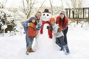 Family Building Snowman In Garden