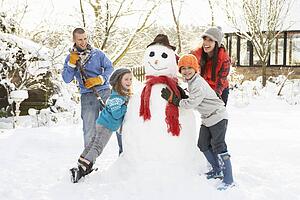 Family Building Snowman In Garden