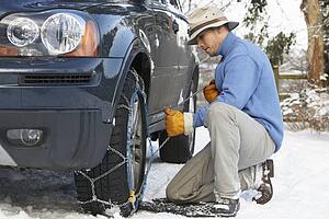 Man Putting Snow Chains Onto Tyre Of Car