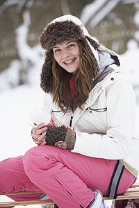 Teenage Girl Sitting On Sledge With Flask And Hot Drink