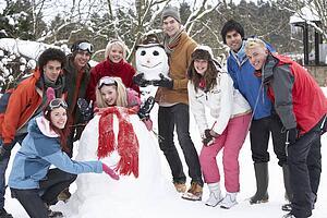 Group Of Teenage Friends Building Snowman In Garden
