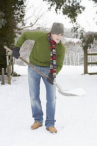 Young Man Clearing Snow From Drive