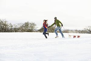 Teenage Couple Pulling Sledge Across Snowy Field