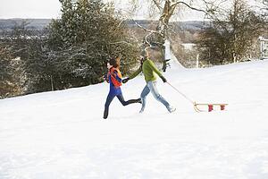 Teenage Couple Pulling Sledge Across Snowy Field
