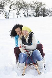 Couple Sledging Through Snowy Woodland
