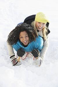 Couple Sledging Through Snowy Woodland