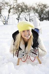 Teenage Girl Riding On Sledge In Snowy Landscape