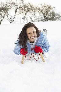 Young Woman Riding On Sledge In Snowy Landscape