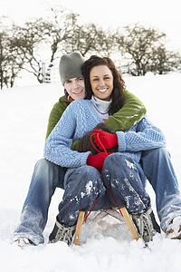 Couple Sledging Through Snowy Woodland