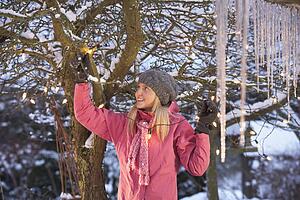 Teenage Girl Hanging Fairy Lights In Tree With Icicles In Foreground