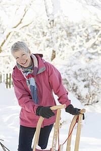 Senior Woman Holding Sledge In Snowy Landscape