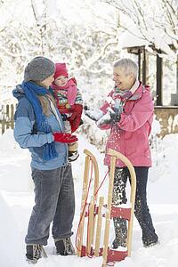 Young Girl With Grandmother And Mother Holding Sledge In Garden