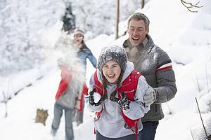Young Family Having Snowball Fight In Snowy Landscape