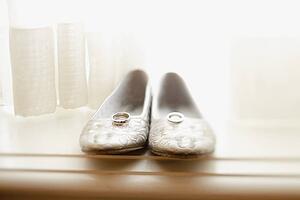 a pair of flat women's shoes with wedding bands on top of them