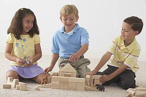 three children building noah's ark with wooden blocks