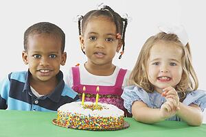 three children with a birthday cake