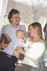 a family with a baby boy and the father holding a bible