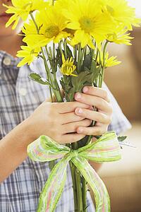 a boy holding a bouquet of yellow daisies