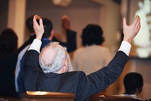 a man sitting in church with hands raised