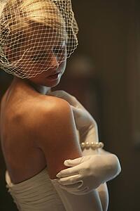 a bride wearing a strapless dress, veil and white gloves