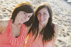 two young women sitting on the beach