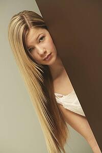 a girl in a white dress hiding behind a wall