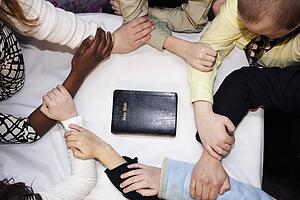 a group of people praying around a bible