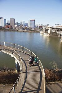 three teenage girls on a pedestrian bridge over a river