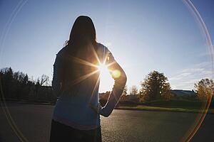 beams of sunlight and a circular glare around a teenage girl
