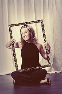 a woman holding a picture frame around her face and torso