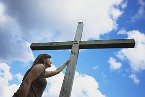 a woman holds on to the cross