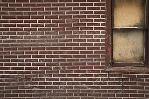 alberta, canada; a red brick wall with a boarded up window