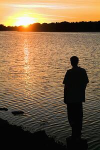 willmar, minnesota, united states of america; silhouette of a man standing on the shore watching the sunset