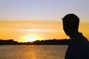 willmar, minnesota, united states of america; silhouette of a man watching the sunset over a lake