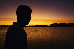 willmar, minnesota, united states of america; silhouette of a man watching the sunset over a lake