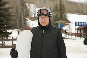 red deer, alberta, canada; a man holding a snowboard wearing a helmet and mask