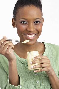 Young Woman Eating Yoghurt In Studio