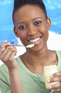 Young Woman Eating Yoghurt In Studio