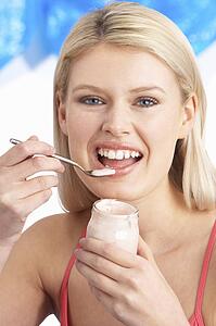 Young Woman Eating Yoghurt In Studio