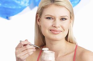 Young Woman Eating Yoghurt In Studio