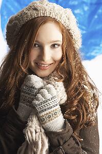 Teenage Girl Wearing Warm Winter Clothes And Hat In Studio
