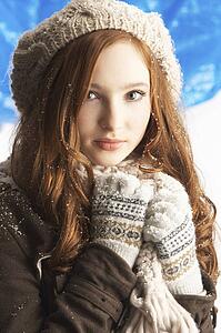 Teenage Girl Wearing Warm Winter Clothes And Hat In Studio